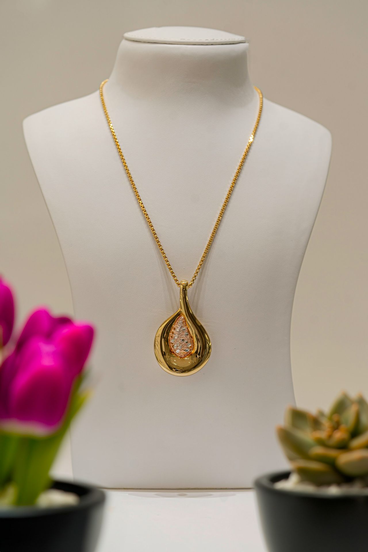a necklace on a mannequin with flowers in the background